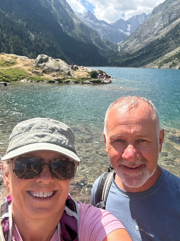 selfie of a couple wearing hiking gear in front of turquoise mountain lake