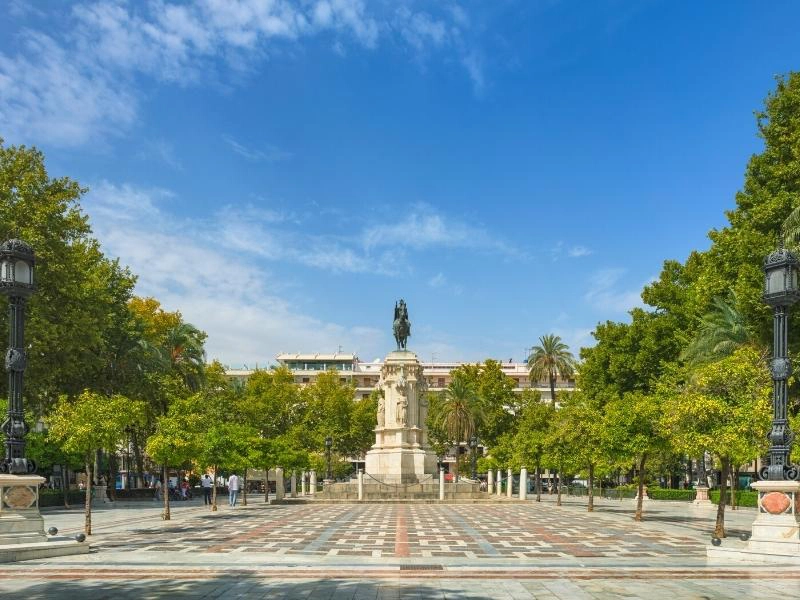 marble statue on a plinth in a leafy square