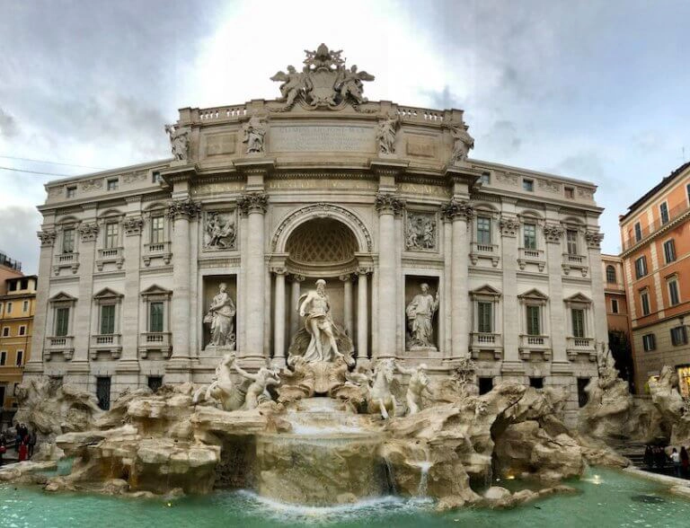 Ornate fountain in Rome in front of a large hsitoric building