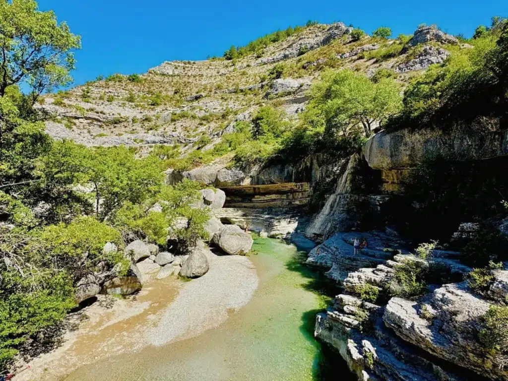 clear sandy river surrounded by a rocky gorge and trees