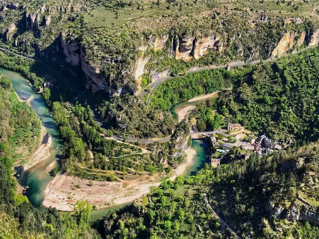 aerial shot of a heavily wooden gorge, small river and river beach