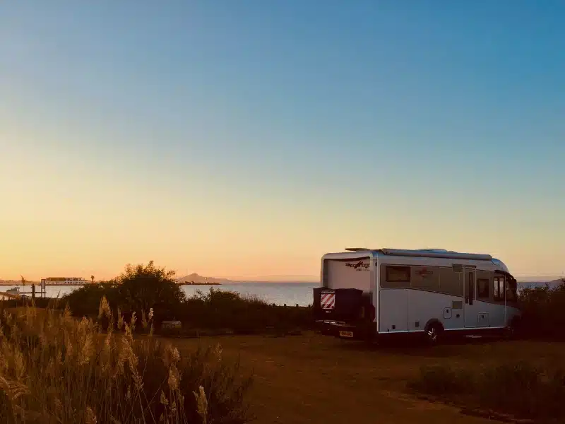 silver motorhome parked amongst reeds and vegitation on a body of water