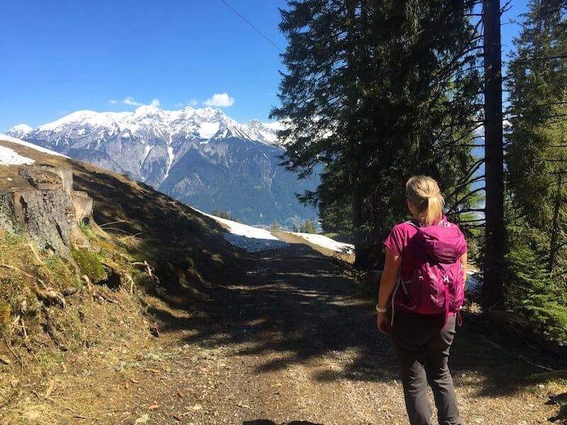 woman wearing a pink t-shirt and ricksack looking towards a large mountain range