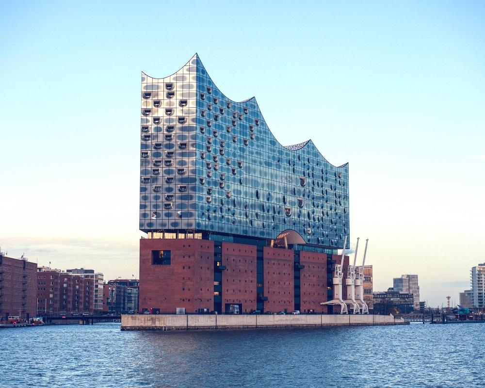 statuesque glass and brick building with the roof shaped like a wave, built by the die of a large river