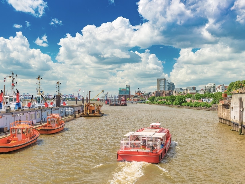 A red ship with tourist is sailing on the Elbe River in Hamburg, Germany