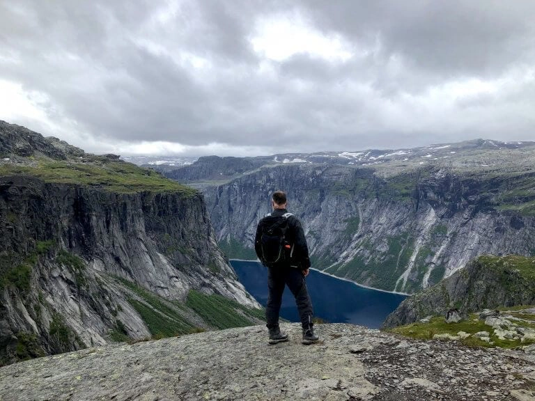 man waering dark walking gear overlooking a lake