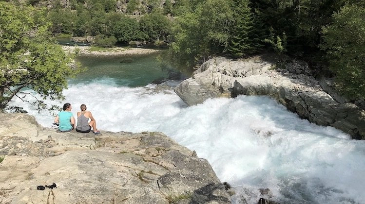 raging waterfall and river with two people sitting by it