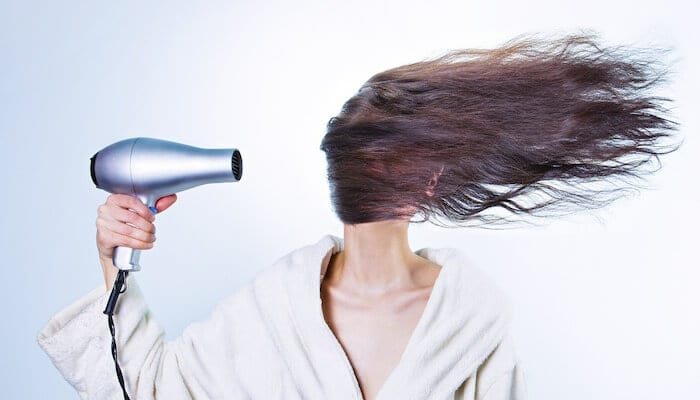 woman using a silver hairdryer