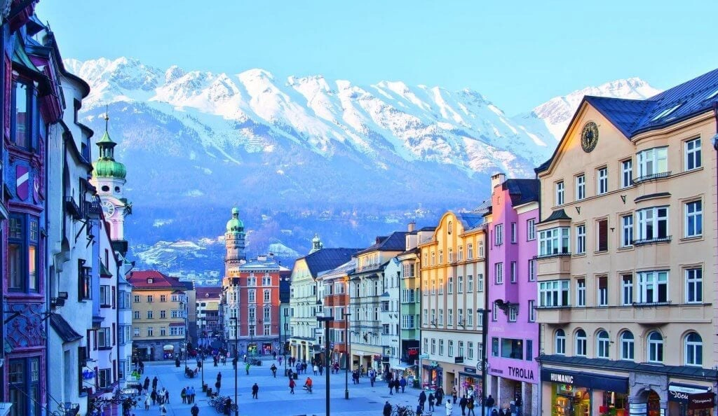 Pedestrian city street with large historic buildings and mountains in the background