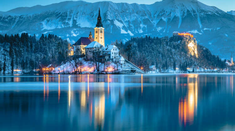 Church reflected in a blue lake with snowy mountain backdrop