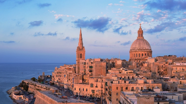 red buildings of a city and a domed church with a sea backdrop