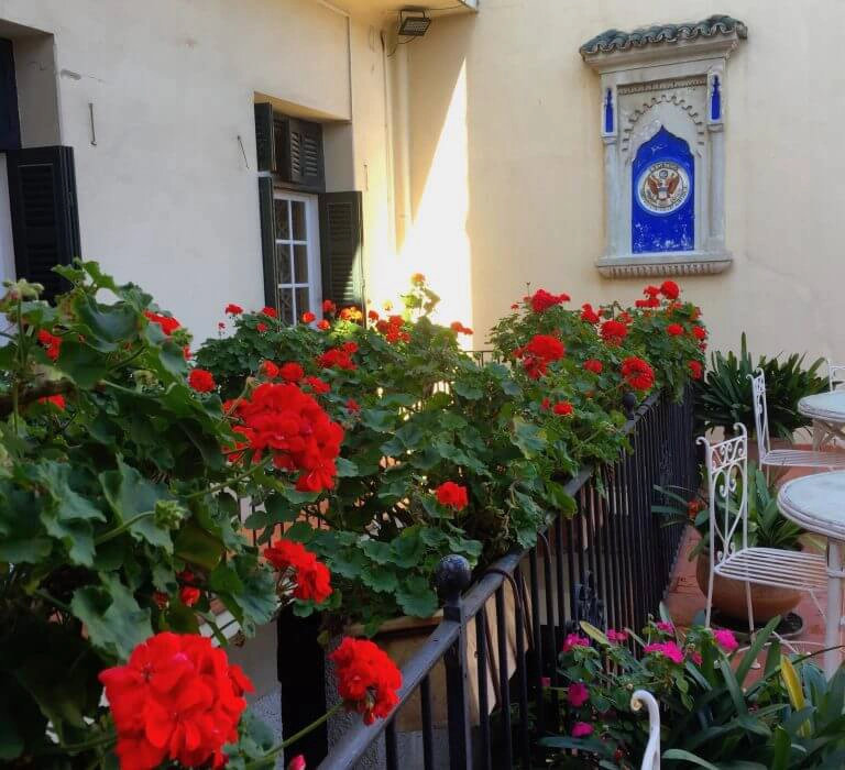 red geraniums in pots on a wrought iron balcony