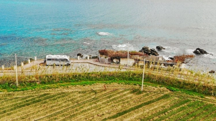 motorhome parked between the sea and a green field