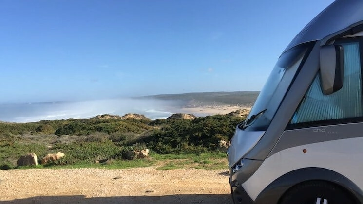 Motorhome parked overlooking a large sandy beach with blue skies