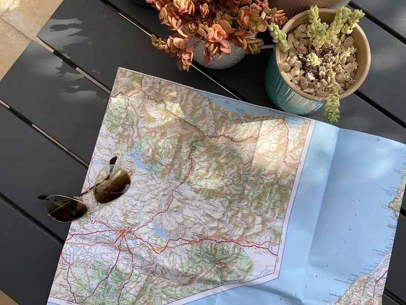 paper map of Porocco spread out on a table with sunglasses and succulents in pots