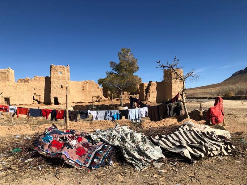 ruined kasbah with a washing line and clothes hung out, with Berber rugs piled up 