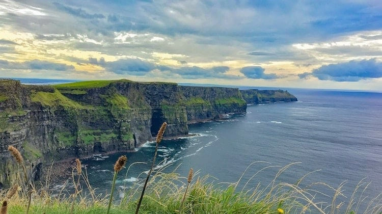 grass topped cliffs in front of steel grey sea and cloudy sky