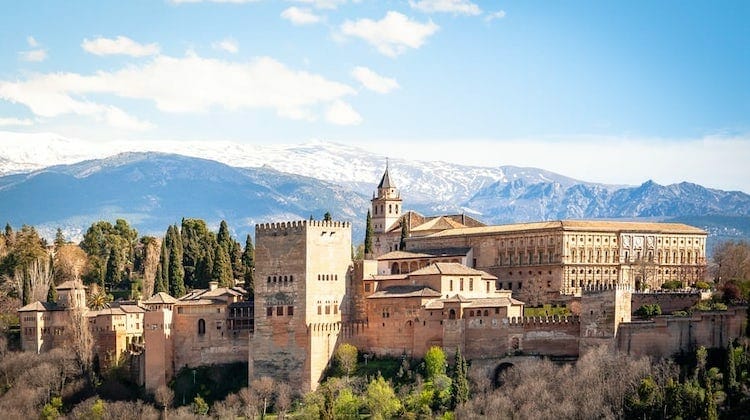 creamy coloured palace with snow capped mountains behind