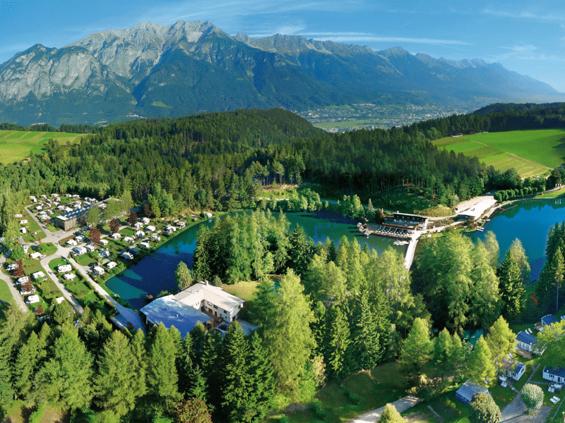 Aerial view of a campiste by a lake with large mountains in the background