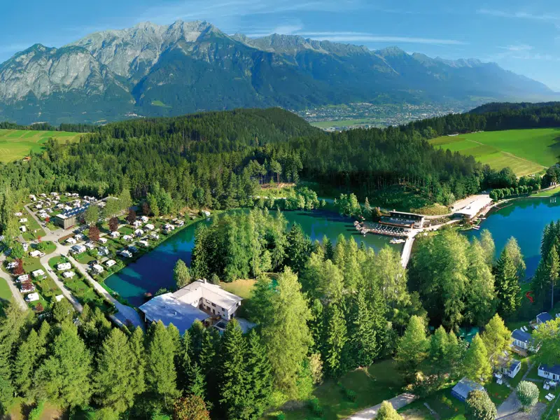 Aerial view of a campiste by a lake with large mountains in the background
