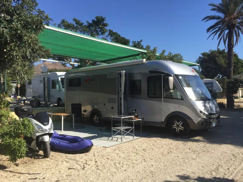 Latge silver motorhome parked on a sandy pitch