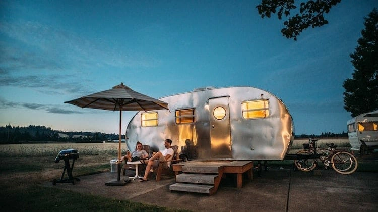 old caravan with wooden steps and a parasol at dusk