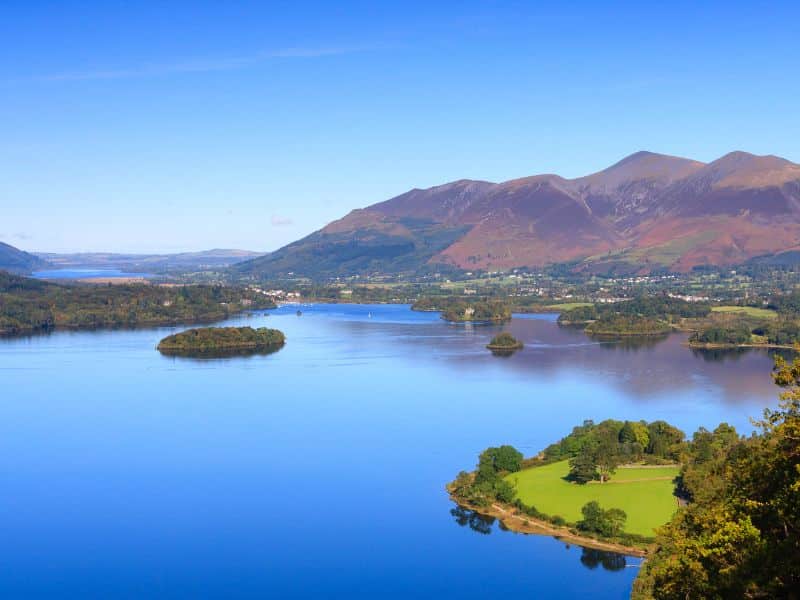 A view across Derwentwater in the English Lake District National Park to the town of Keswick and beyond is Skiddaw.