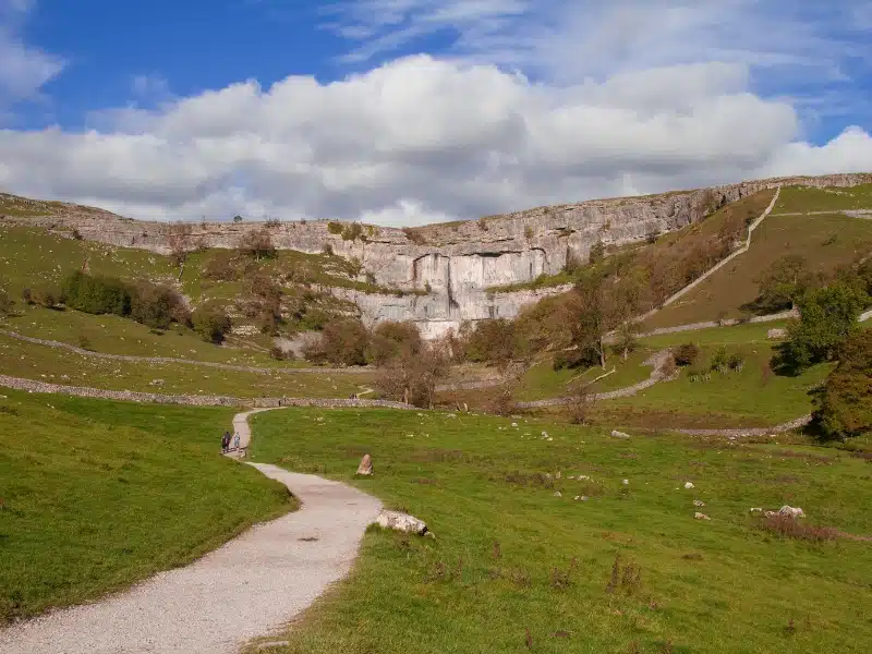 cliff scar surrounded by grassy meadows with a path through them