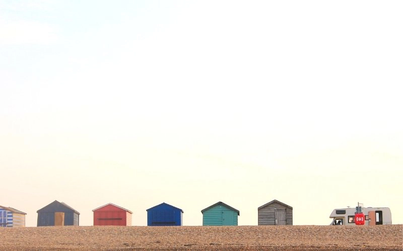 colourful beach huts with a motorhome parked at one end