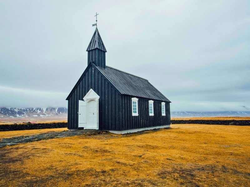 Black clad church with a dramatic mountain backdrop