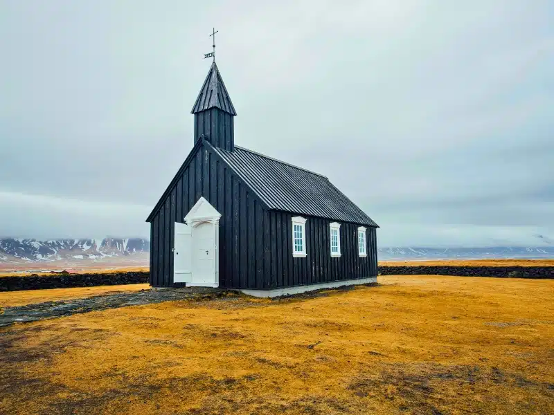 Black clad church with a dramatic mountain backdrop