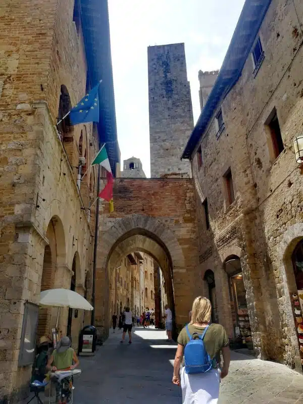 blonde woman with a blue rucksack in a medieval cobbled street