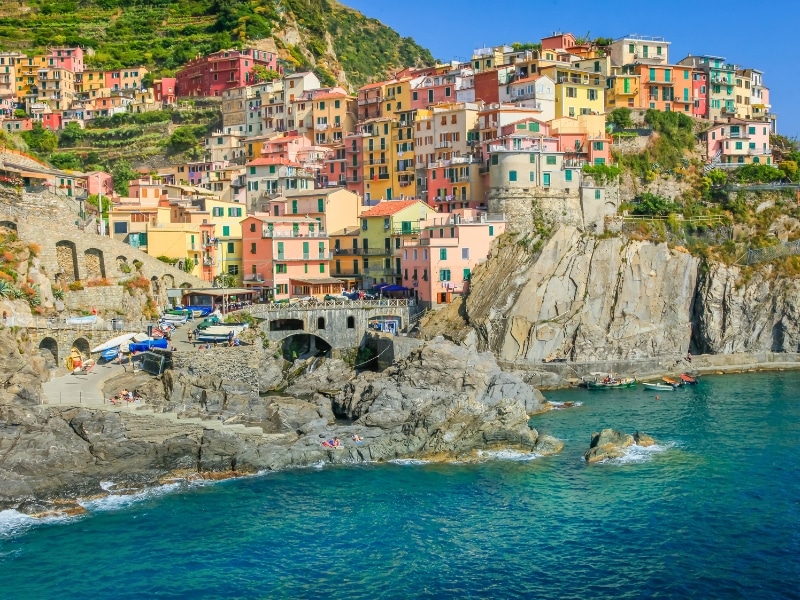 colorful houses stacked along. arocky shore with turquoise water