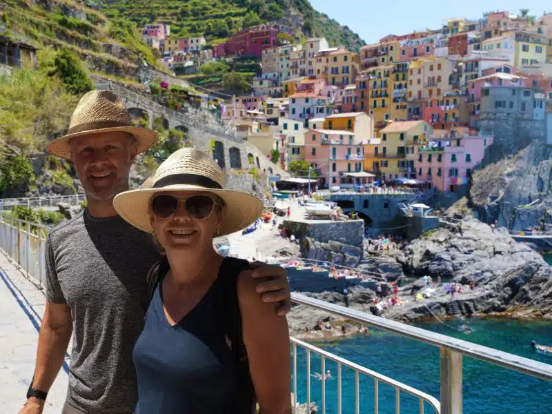 Couple standing in front of a seaside town with pastel painted houses