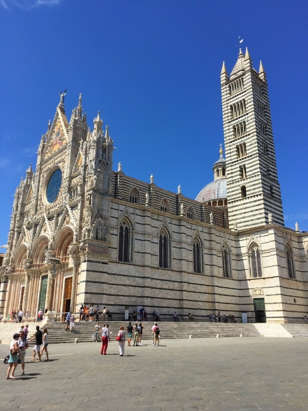 White and black marble cathedral with striped tower and ornate doors