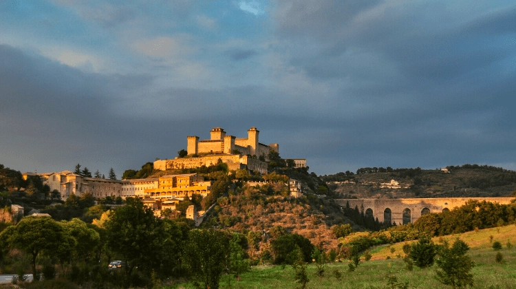 Town on a hill topped with a large castle in front of stormy skies