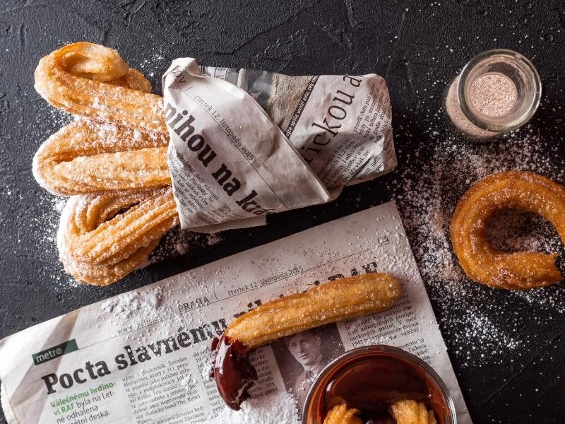 churros sprinkled with sugar wrapped in newspaper