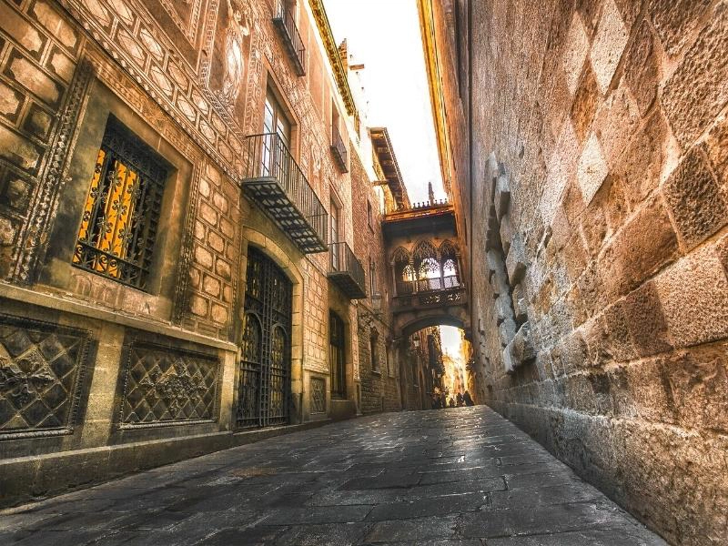 Cobbled alley with ornate bridge between historic buildings