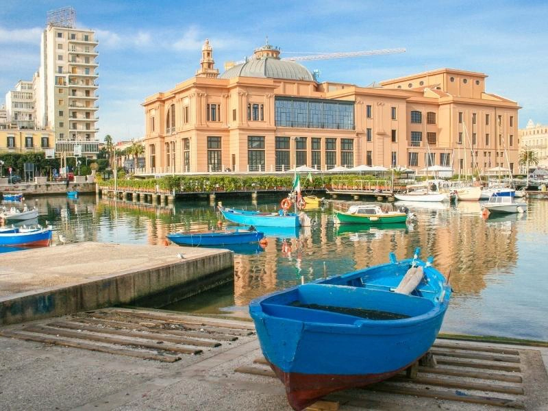 blue boats in an inslet inf ront of rose colored building