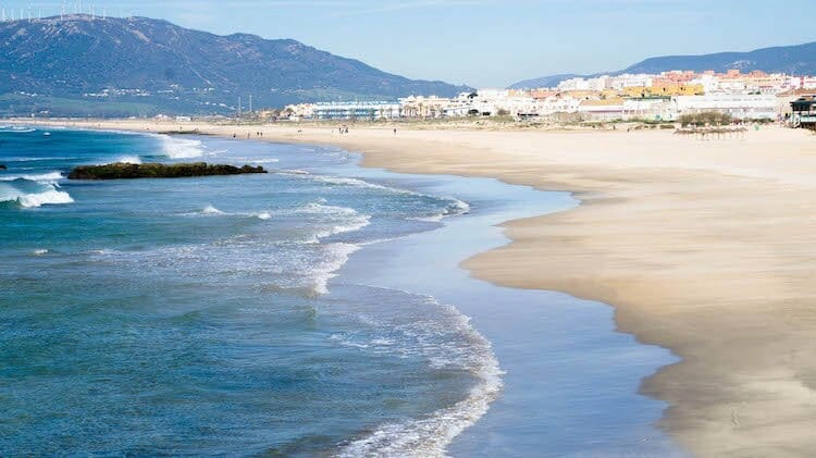 Long sandy beach and blue sea with small waves in Tarifa Spain