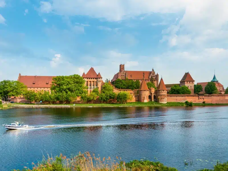 large red brick castle with turrets on a lake