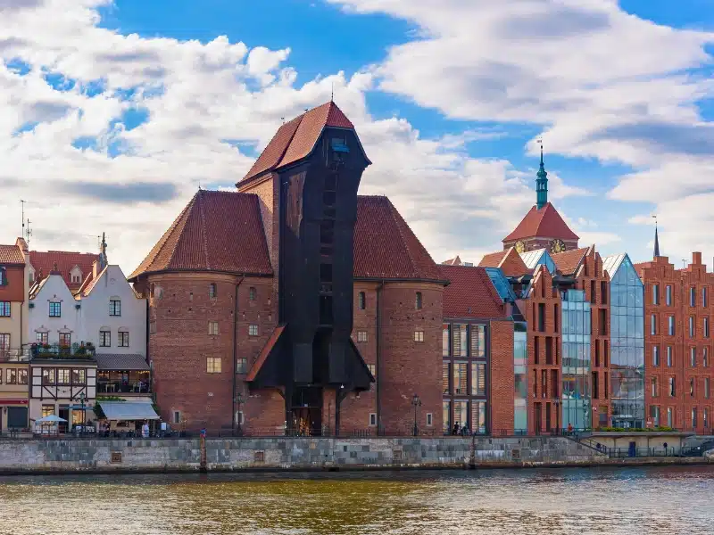 Medieval port crane in the old town of Gdansk with the river in front and buildings to either side