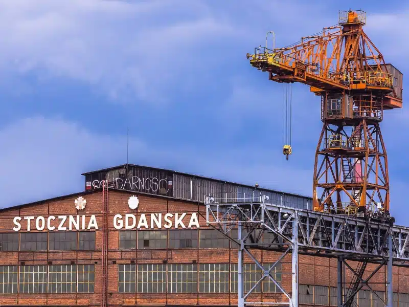 large orange crane over a brick and glass warehouse building