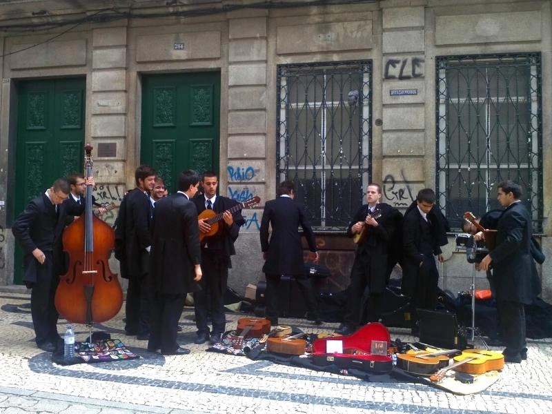 men in suits with guitars and other instruments on a cobbled street