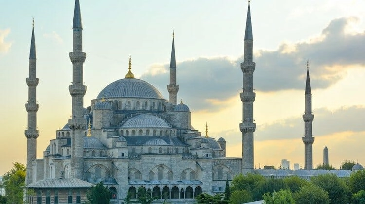 Large white mosque with five minarets against a blue and yellow wintery sky