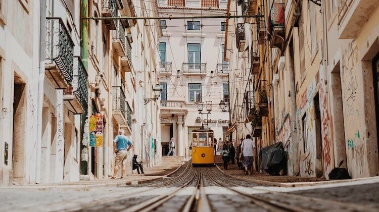 A yellow tram coming down a street in Lisbon