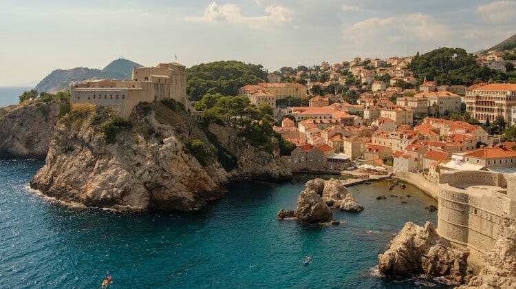 Creamy walls and red roofs behind blue sea glinting in the winter sun