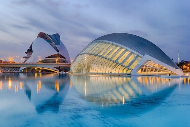 Modern white buildings lit up at twilight and surrounded by blue water