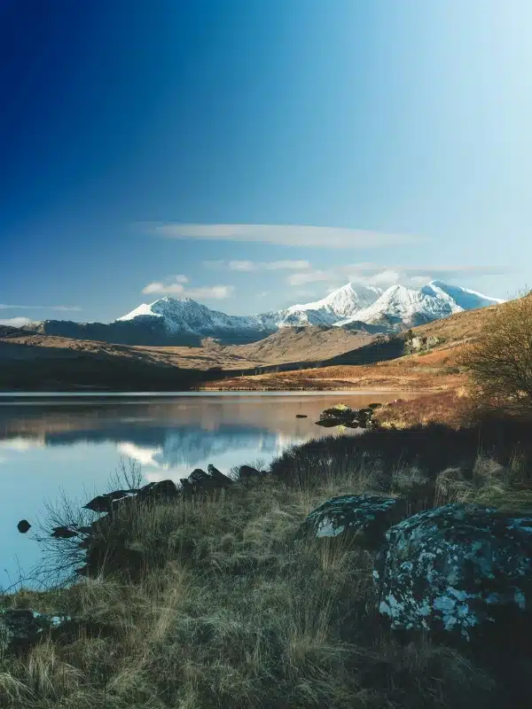 Autumnal foliage arround. amirror lake with snow covered mountains in the distance