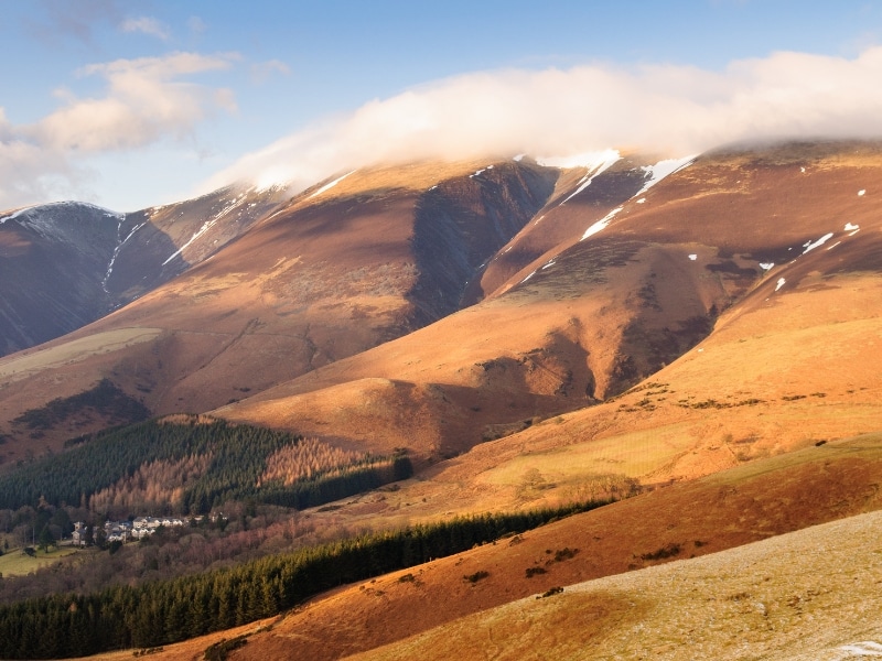 mountains with light snow and clouds at the peak in autumn colors